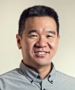 Kevin Sakamoto Director of Product Management, Dollar Shave Club, smiling with short black hair wearing a buttoned gray shirt against a light background.