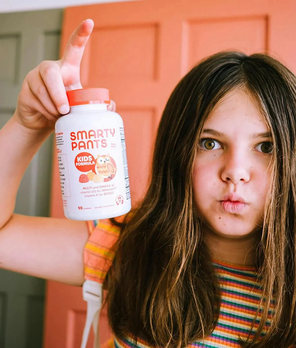 Little girl holding a SmartyPants kids formula bottle